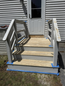 Newly constructed outdoor wooden stairs with railings, partially painted white, by Daniels Handyman Services in Warwick, RI.