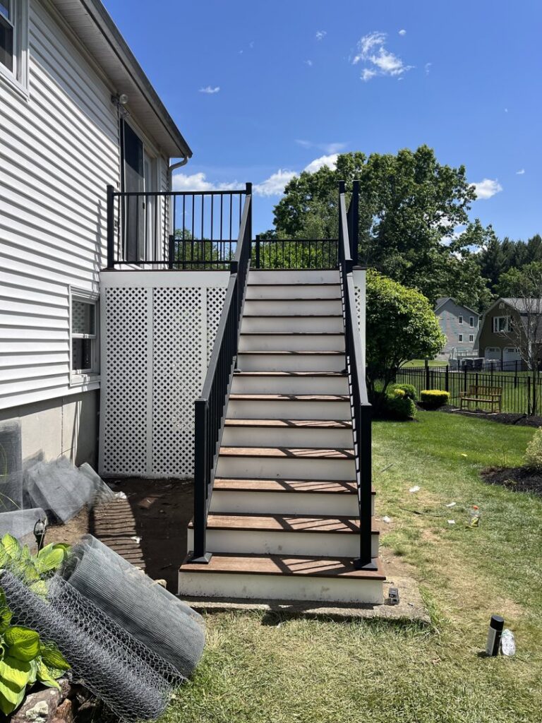 A newly constructed outdoor staircase with black railings and brown steps, built by Men Construction in Lowell, MA.
