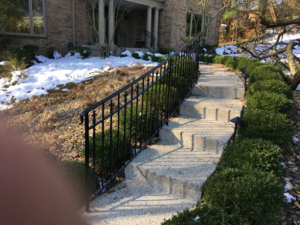 An outdoor stone staircase with a newly installed black metal railing by Glen E Stuckel Builder LLC in Louisville, KY.
