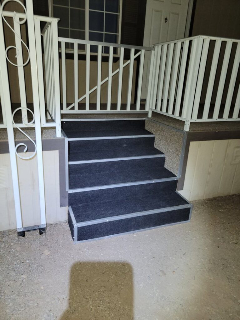 Newly installed outdoor steps with carpet and white railings, completed by McCarran Handyman Services in Boulder City, NV.