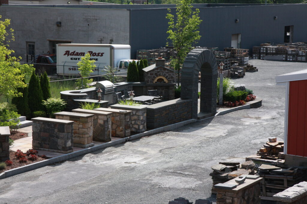 An outdoor display area showcasing stone kitchen, pizza oven, and archway projects by Adam Ross Cut Stone in Albany, NY.
