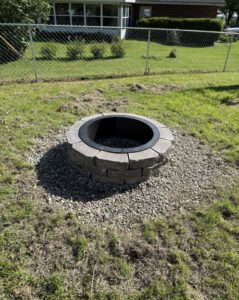 A newly installed stone fire pit on a gravel base in a backyard by Lankford Dirt Works LLC in Indianapolis, IN.