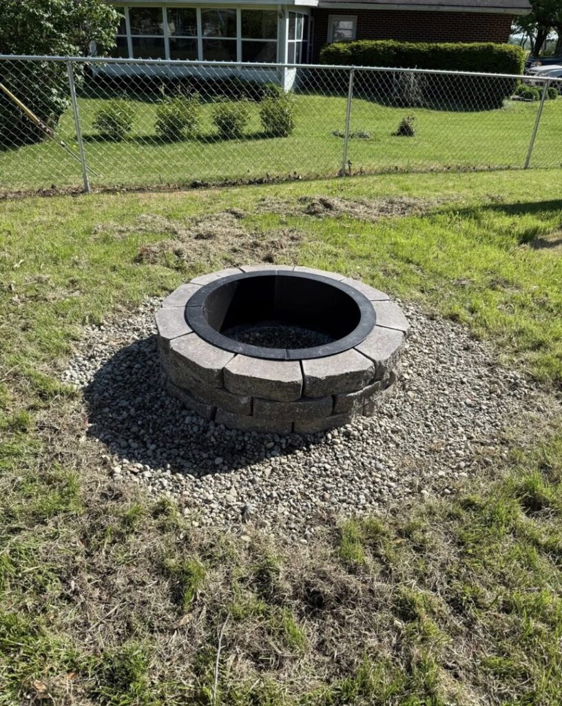 A newly installed stone fire pit on a gravel base in a backyard by Lankford Dirt Works LLC in Indianapolis, IN.