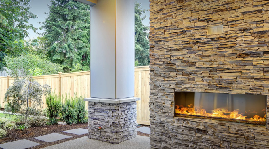An outdoor living space featuring a modern stone fireplace and patio installed by Punchlistit in Lenexa, KS.