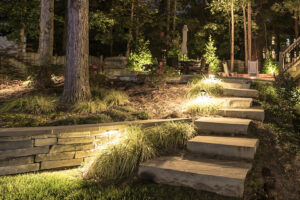 Outdoor stone steps with integrated landscape lighting and a stone retaining wall by Constructive Design Group in Raleigh, NC