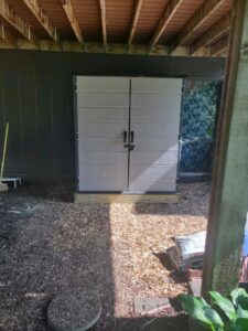 A newly assembled outdoor storage shed placed on a wooden base by IFixdIt Handyman Services in Omaha, NE.