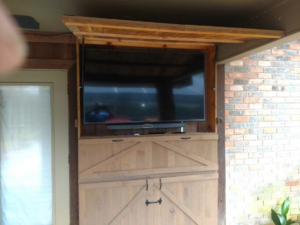 A custom-built outdoor TV cabinet with a mounted television, installed by Rex Austin's Remodeling in Ball, LA.