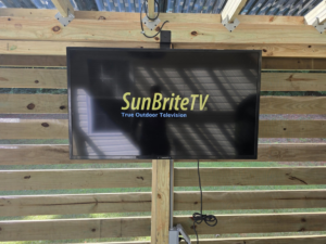 An outdoor TV professionally mounted on a custom-built wooden pergola structure by S&L Decking and Fencing in Charlotte, NC.