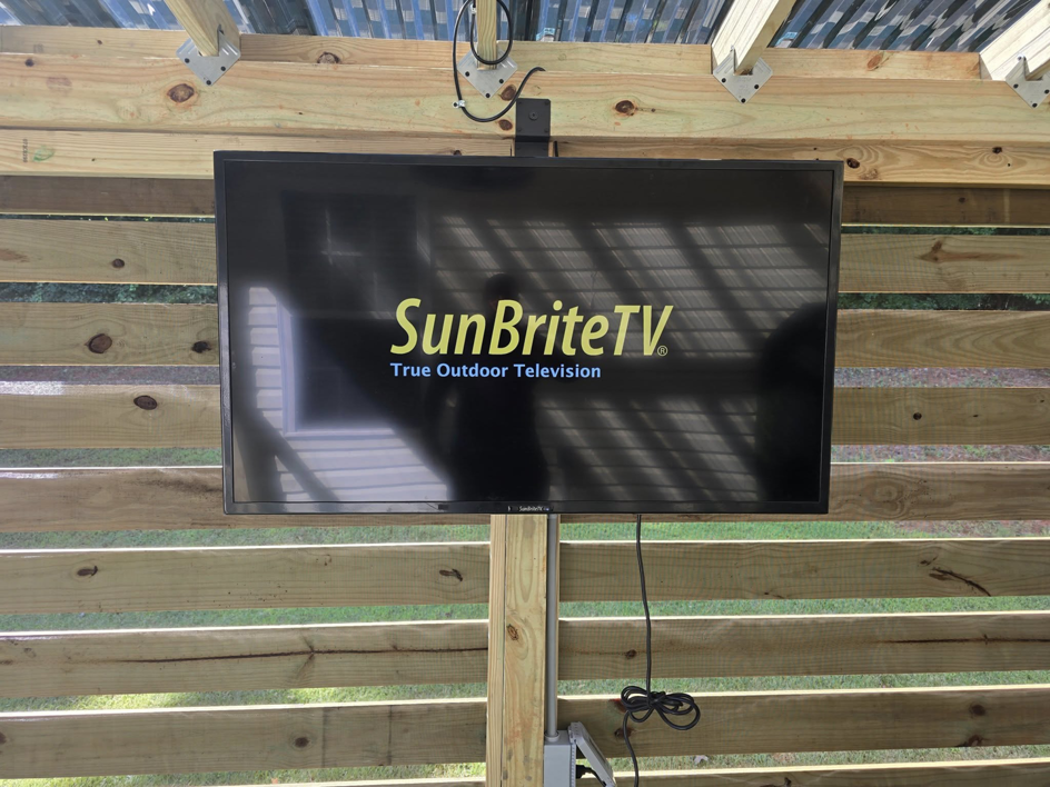 An outdoor TV professionally mounted on a custom-built wooden pergola structure by S&L Decking and Fencing in Charlotte, NC.