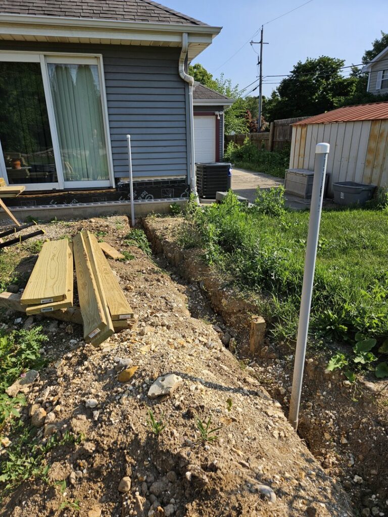 An outdoor trench with pipes and lumber, indicating utility line installation by Paramount Development in Milwaukee, WI.