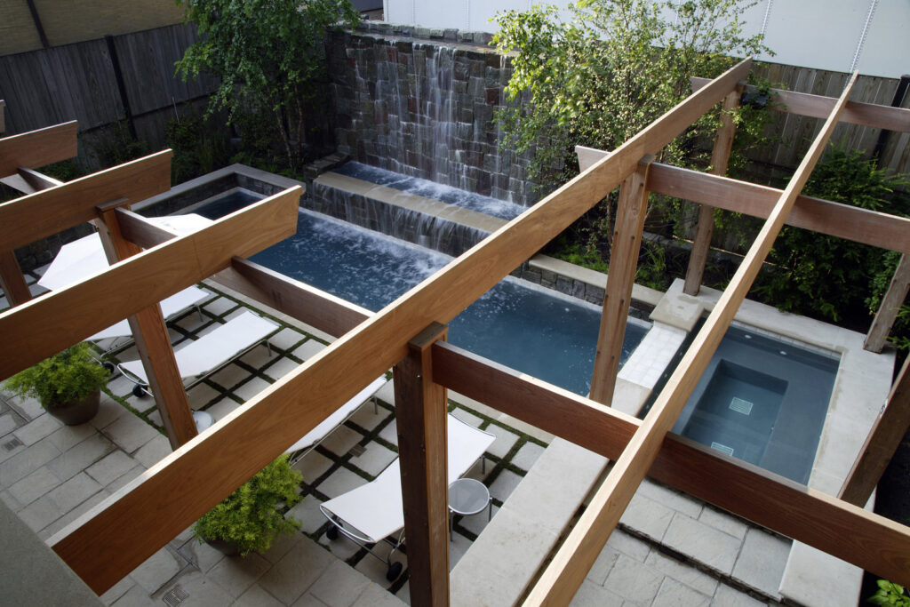 An outdoor area featuring multiple water features, a stone waterfall, and a wooden pergola by S.N. Peck Builder, Inc. in Chicago, IL.