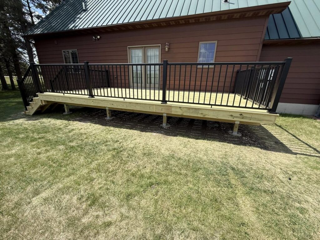 Newly installed outdoor wooden deck with black metal railings, a project by Watertown Handyman in Watertown, SD.