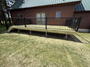 Newly installed outdoor wooden deck with black metal railings, a project by Watertown Handyman in Watertown, SD.