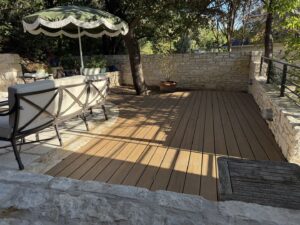A beautiful outdoor wooden deck and patio area with natural stone walls by Transformations Custom Build in Austin, TX