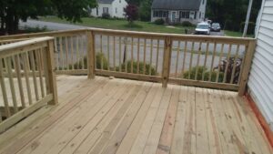 An outdoor wooden deck with railings, offering a view of the street, built by Modern Remodel Build & Design in Worcester, MA.