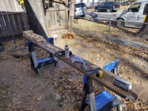 An outdoor workbench with wood pieces, glue, and tools ready for a project by Do-N-All Handyman Service in Wichita, KS.