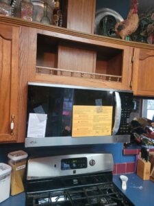 An over-the-range microwave being installed above a stove by Friendly Handyman LLC in Wichita, KS