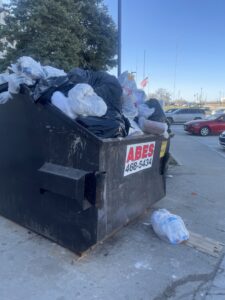 An overflowing dumpster from Abe's Trash Service, Inc. filled with trash in Omaha, NE.