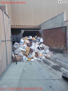 An overflowing dumpster with a large pile of trash and junk, indicating a commercial junk removal need in Augusta, ME.