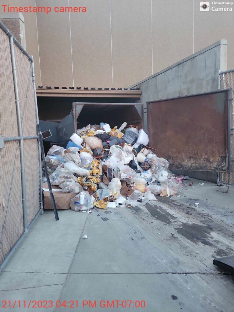 An overflowing dumpster with a large pile of trash and junk, indicating a commercial junk removal need in Augusta, ME.