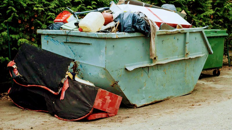 A large, overflowing dumpster filled with various debris and trash, indicating a significant junk removal project handled by Trash Monkey Junk Removal in Charleston, WV.