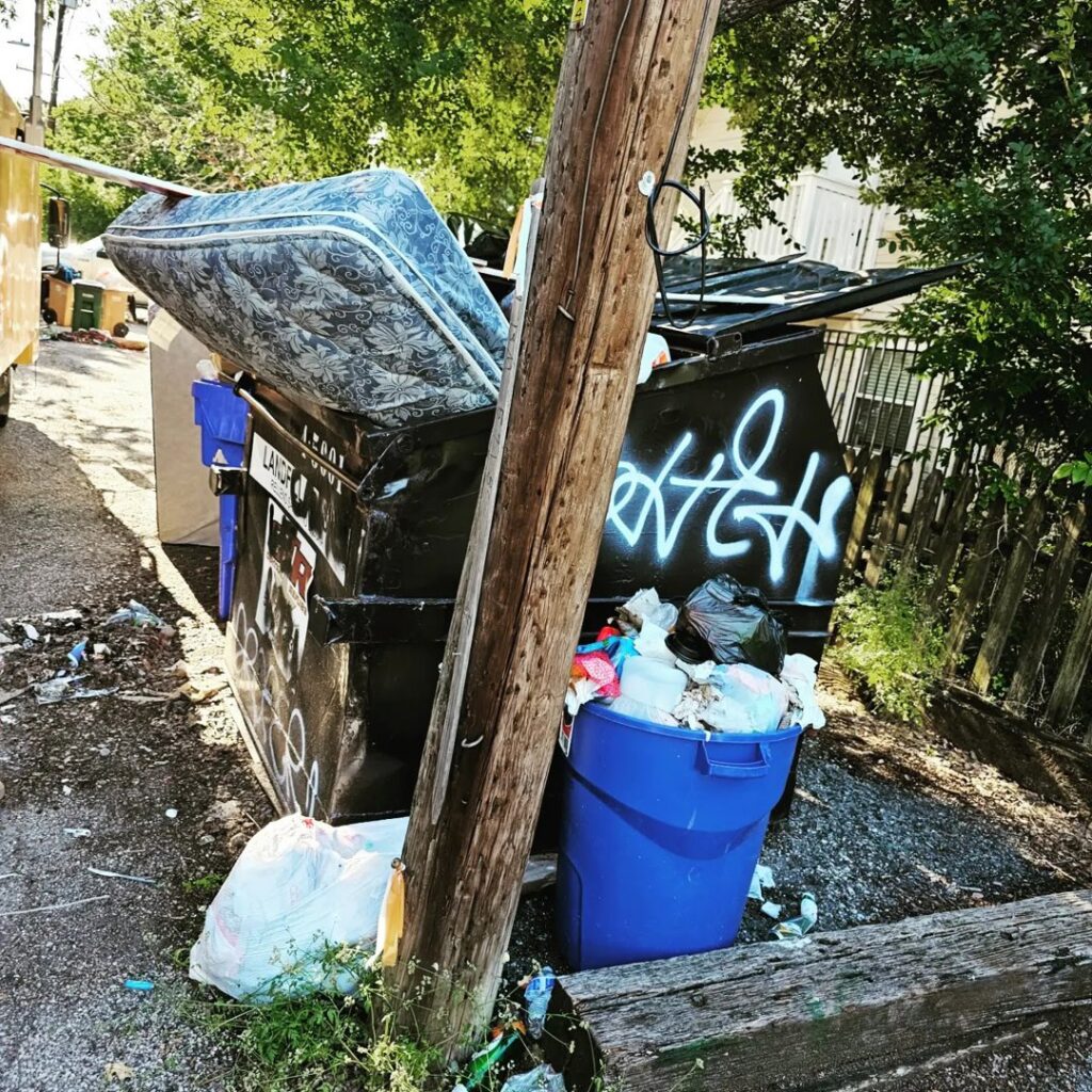 An overflowing dumpster with a mattress and other junk, indicating a large-scale removal by Junk Out Boyz LLC in Georgetown, TX.