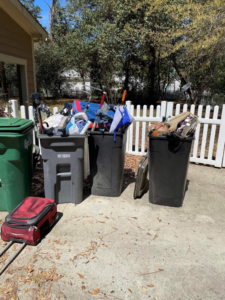 Overflowing trash bins with golf clubs, bags, and junk outside a house, removed by Show Us Ur Junk in Fayetteville, NC.