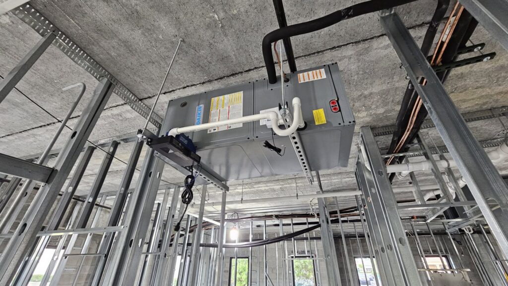 Overhead HVAC unit and ductwork installation within metal framing at a construction site by Belair Inc. in Saint Cloud, FL