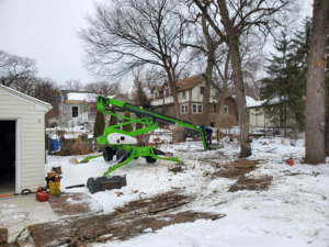 An overhead view of tree trimming work from an aerial lift, showing cut branches on the snowy ground by Beaver Tree Service in Des Moines, IA