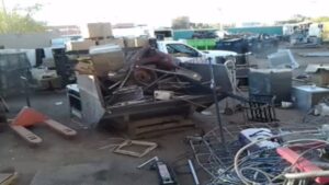 An overview of a busy scrap yard and recycling facility, showing various piles of metal and junk at RZR Mechanical LLC in Phoenix, AZ.