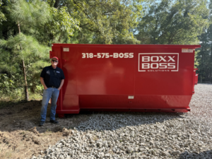 An owner standing proudly next to an empty junk removal dumpster from Boxx Boss Solutions in Bossier City, LA.