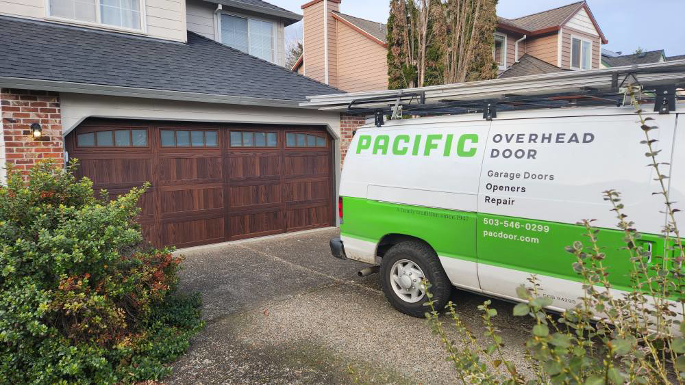 A Pacific Overhead Door van parked in front of a home with a newly installed brown garage door in Portland, OR.