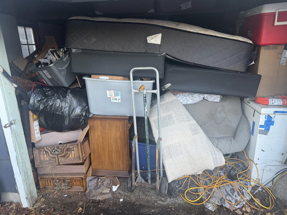 A shed packed with a mattress, furniture, boxes, and other items, ready for junk removal by Junk Management in Vancouver, WA.