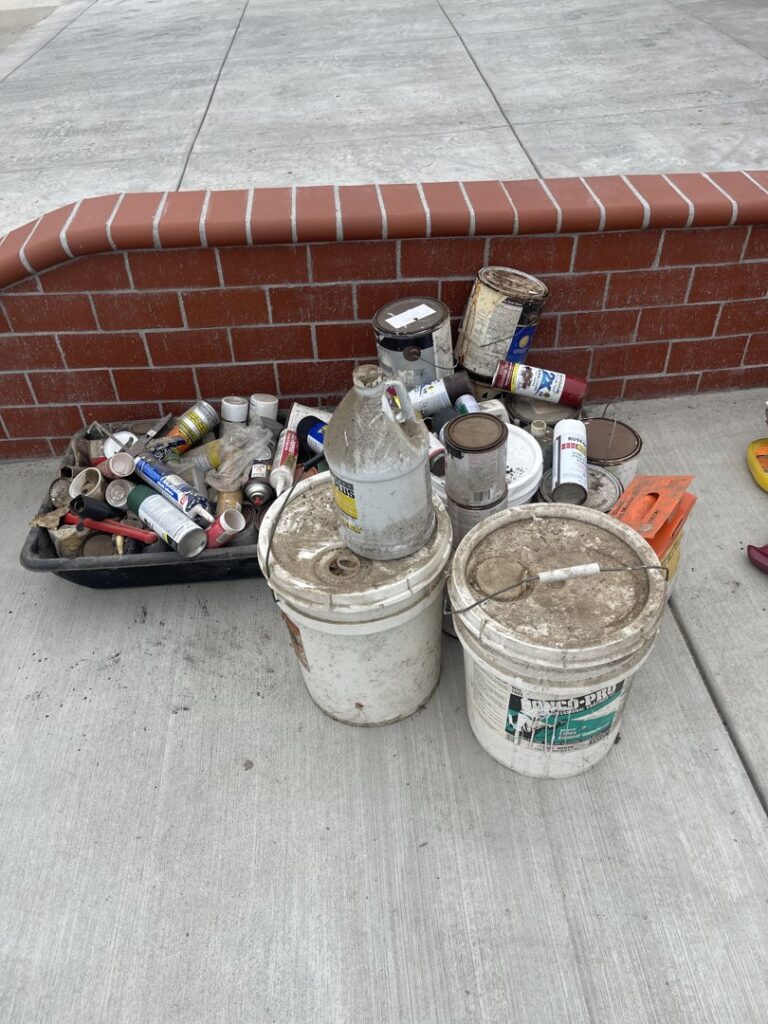 Paint cans and other hazardous materials collected on a sidewalk for removal by Hazawaytoday.com in El Segundo, CA