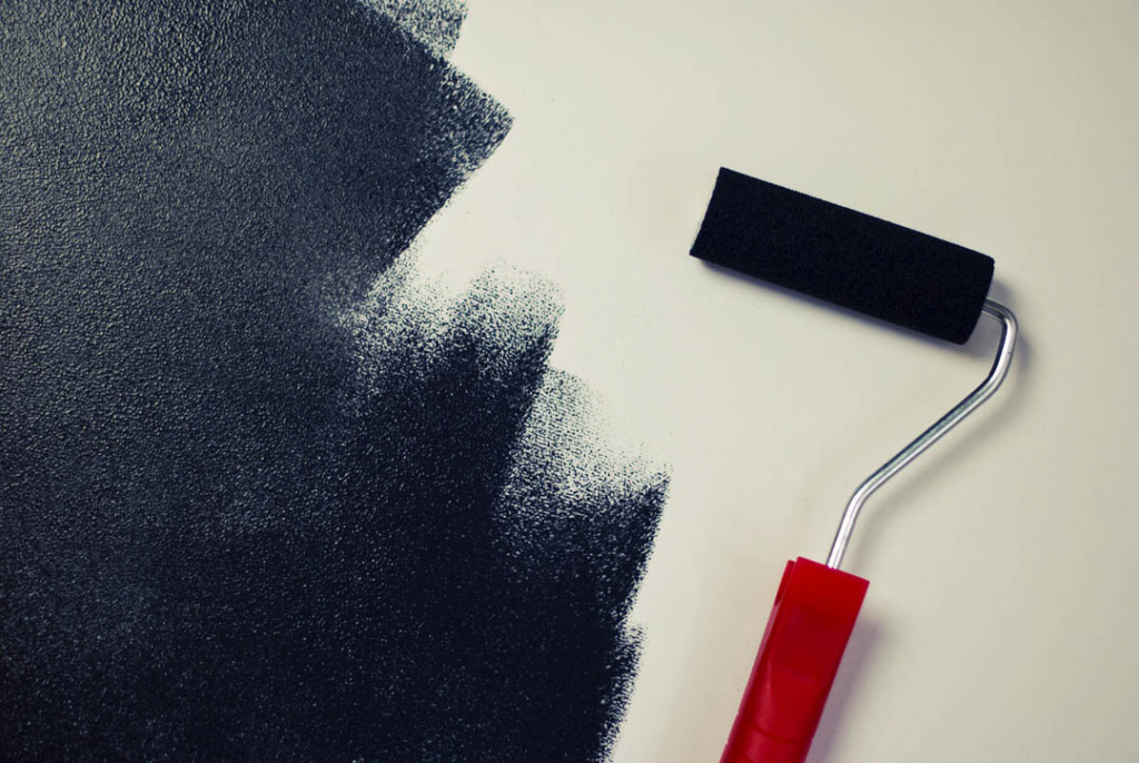 A paint roller applying black paint to a wall, representing painting services by World General Construction LLC in Everett, WA.