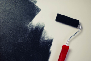 A paint roller applying black paint to a wall, representing painting services by World General Construction LLC in Everett, WA.