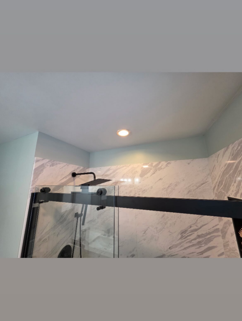 A bathroom wall above the shower tiles freshly painted during a renovation by Precision Property Services LLC in South Windsor, CT.