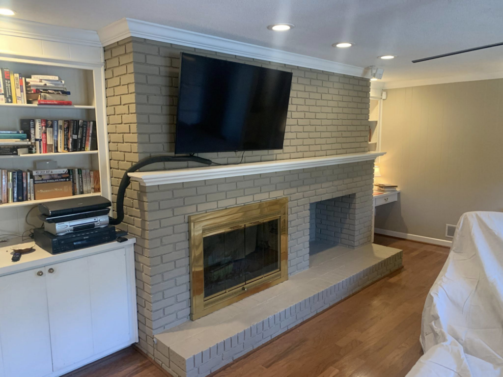 A newly painted brick fireplace with a mounted television and built-in shelves completed by Carolina Handyman Builder in Taylors, SC.