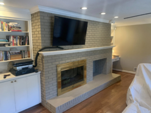 A newly painted brick fireplace with a mounted television and built-in shelves completed by Carolina Handyman Builder in Taylors, SC.