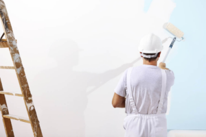 A professional painter in a hard hat and white overalls painting a wall with a roller for World General Construction LLC in Everett, WA.