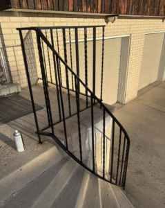 A black metal railing on a front porch being painted by Titan Handyman Services in Lewes, DE
