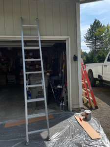 Ladders, paint cans, and drop cloths set up for a painting job by Shed Crafters in Sycamore, IL.