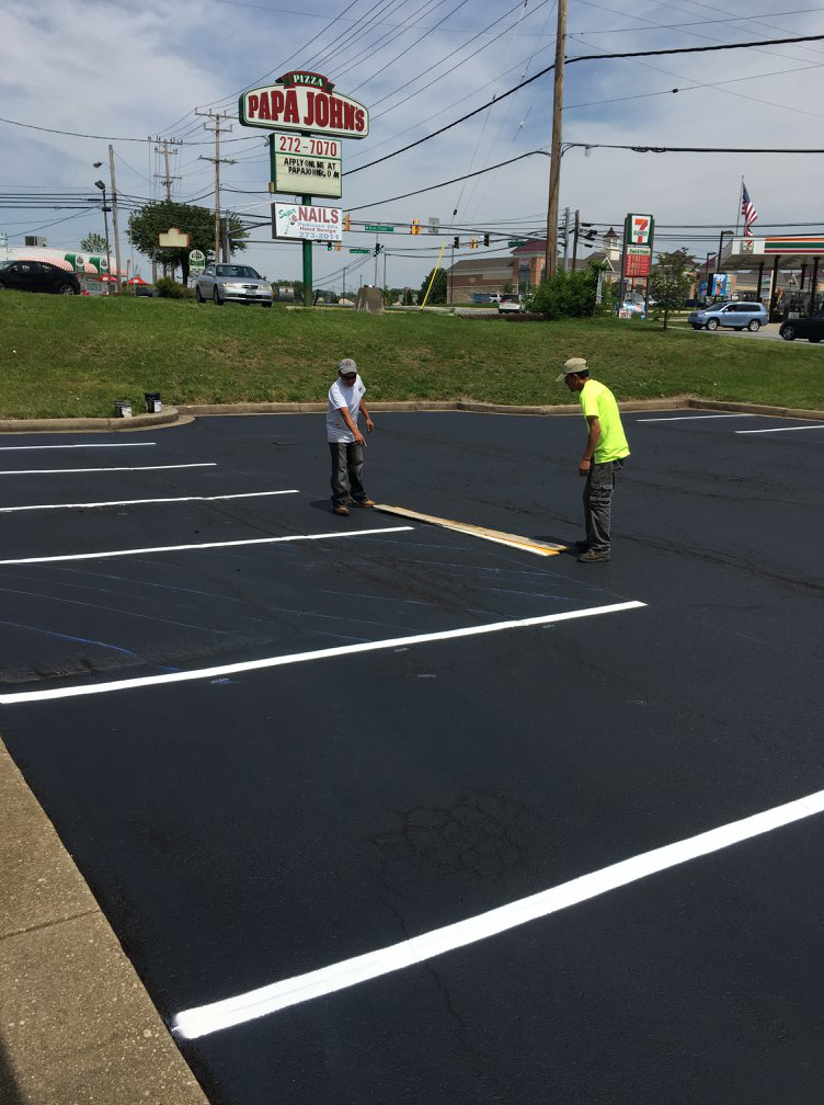 Workers preparing for parking lot striping after sealcoating by Free State Contracting Company in Annapolis, MD