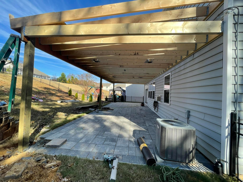 A partially constructed wooden patio cover attached to a house by A.G Deck & Painting in Charlotte, NC.