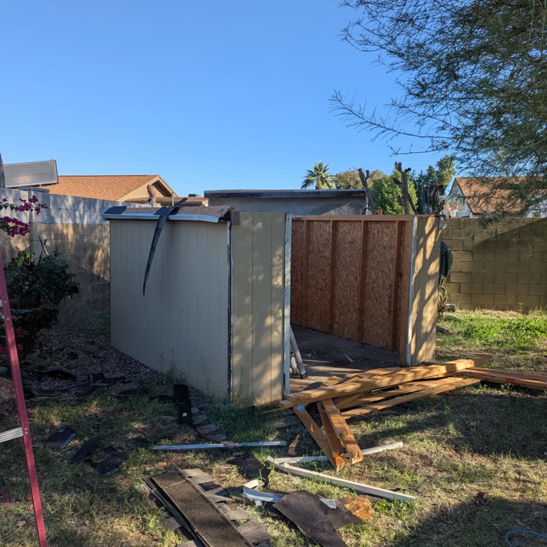 A partially demolished shed with wood debris in a backyard, showing a junk removal job by J & R Junk Removal in Phoenix, AZ.