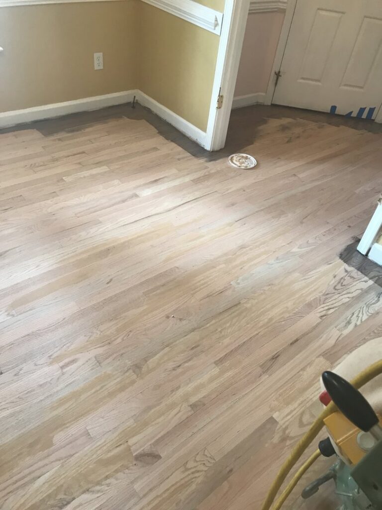 A hardwood floor partially sanded, showing the refinishing process in progress by Franco's Hardwood Flooring in Durham, NC.