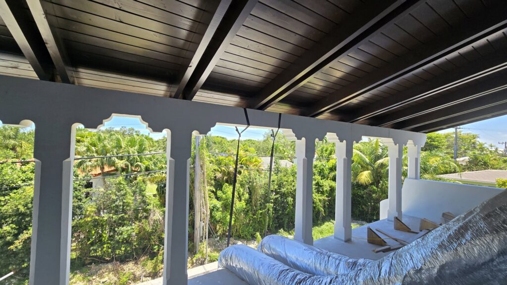 An outdoor patio or balcony under construction, showing exposed beams and HVAC ducts, managed by Cornerstone Services Management in Miami, FL.