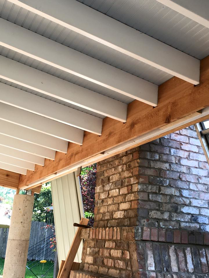Outdoor patio ceiling under construction next to a brick chimney by Felipe Garcia Remodeling and Construction in Mobile, AL.