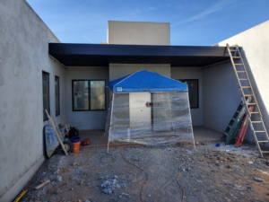 Outdoor patio construction with a tent, ladders, and building materials during an exterior renovation by AV Handyman Services in Rio Rancho, NM.
