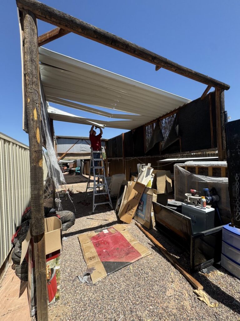 A person working on a patio cover structure surrounded by boxes and junk, indicating removal services by HAVOC Demolition in Scottsdale, AZ.